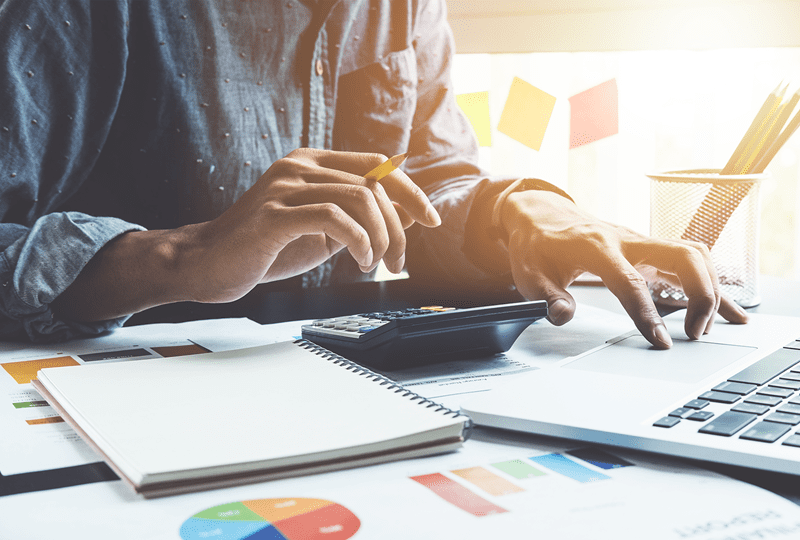 person at table with calculator going through their finances