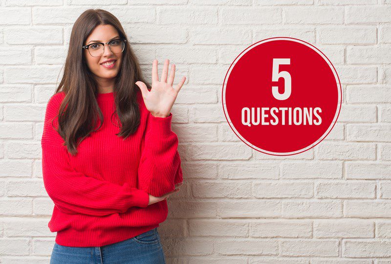 Woma in red shirt against beige wall, with a red circle on the wall, text says, "5 Questions".